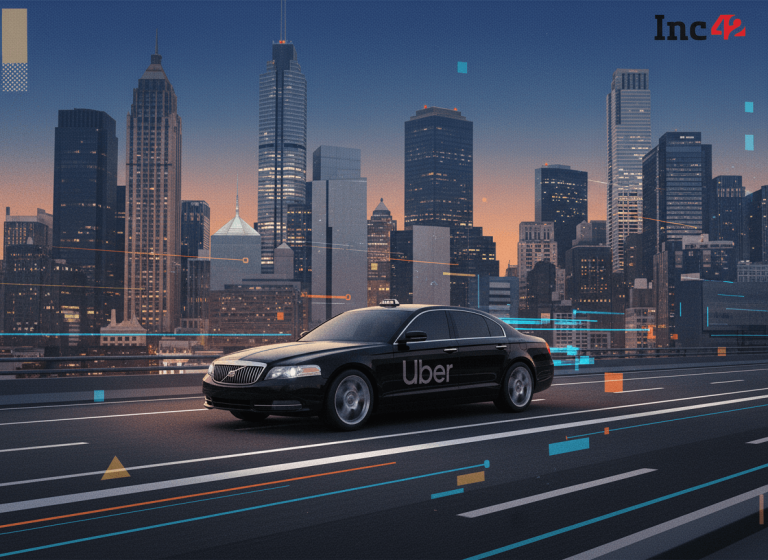 A sleek black Uber car drives on a multi-lane highway with a vibrant, illuminated city skyline in the background at dusk.