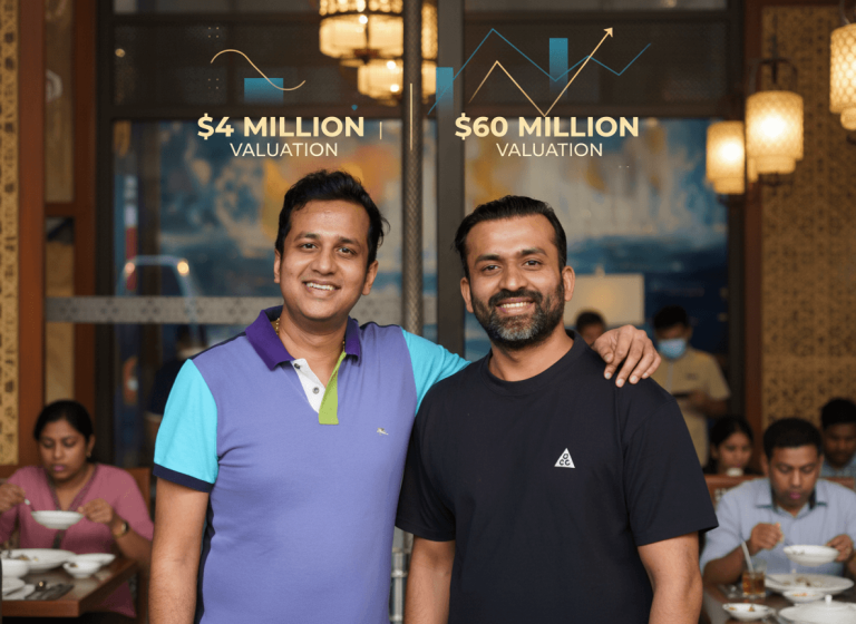 Two smiling founders of Burma Burma in a restaurant with financial growth graphics.